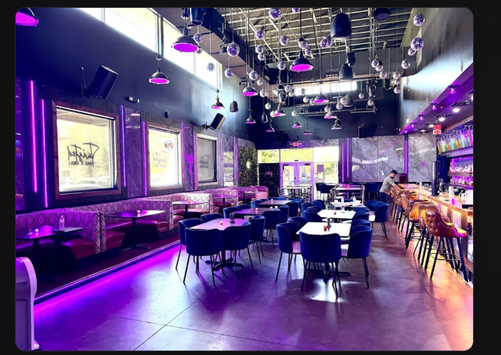 Upscale lounge interior with booth seating, bar, and neon lighting at Twisted Bar and Grill